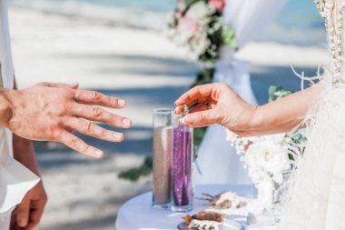 Gelin ve damat, Dominik Cumhuriyeti, Punta Cana 'da okyanusun kıyısındaki kumsalda deniz manzaralı düğün sırasında yüzüklerini değiş tokuş ediyorlar.  