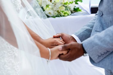 Gelin ve damat, Dominik Cumhuriyeti, Punta Cana 'da okyanusun kıyısındaki kumsalda deniz manzaralı düğün sırasında yüzüklerini değiş tokuş ediyorlar.  