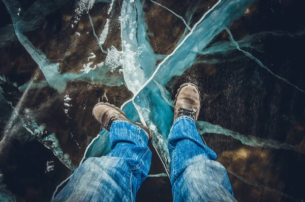 man in jeans and boots on transparent ice