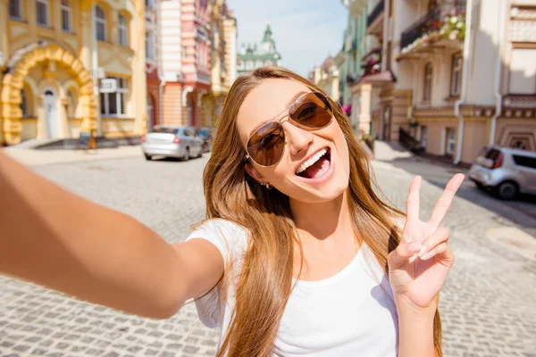 Hezká mladá žena v brýle dělat selfie a shwing dva finge — Stock fotografie