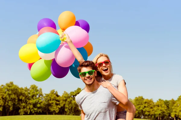 Portret van gelukkig man met ballonnen meeliften zijn vriendin — Stockfoto