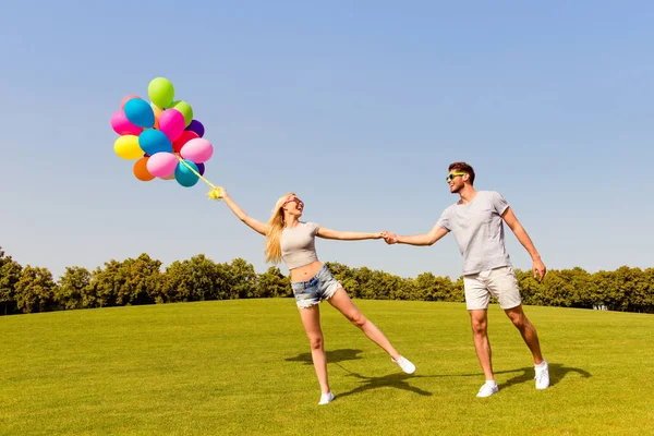 Homme heureux attrapant sa petite amie de ne pas voler avec des ballons — Photo