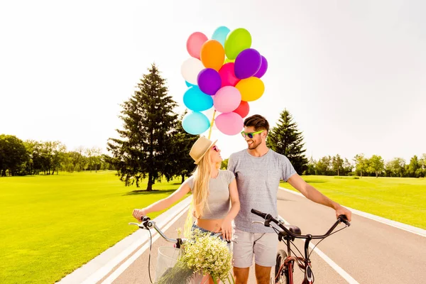 Портрет счастливой влюбленной пары, гуляющей с велосипедами и баллоном — стоковое фото