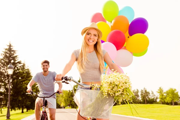 Portret van mooie vrouw met ballonnen en bloemen rijden bik — Stockfoto