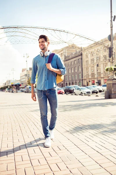 Jovem elegante cara com mochila e fones de ouvido andando na ci — Fotografia de Stock