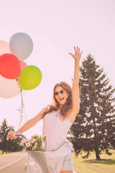 Docela rád, mladá žena s balónky s zvýšené h a jízdních kol — Stock fotografie