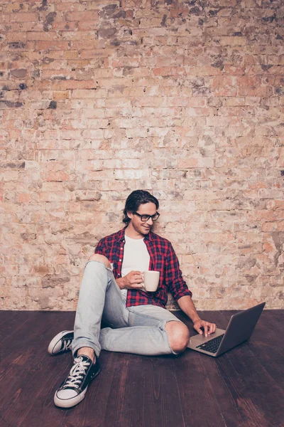 Jonge Spaanse man met kop koffie te typen op laptop — Stockfoto