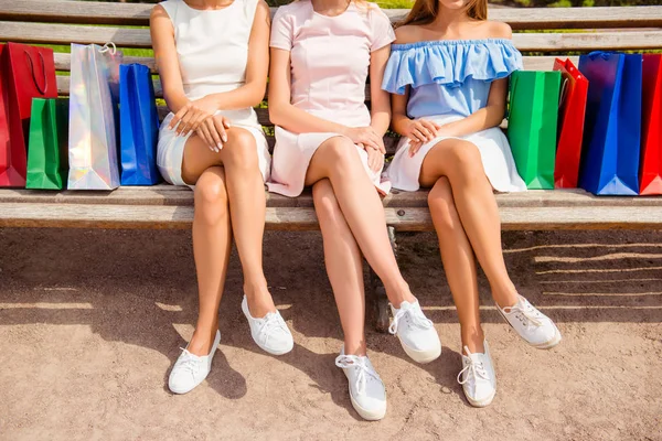 Close up de três mulheres de tênis branco sentado no banco com — Fotografia de Stock