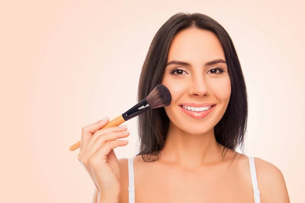 Feliz joven mujer sosteniendo cepillo de maquillaje sobre fondo rosa —  Fotos de Stock