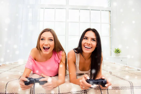 Gelukkig sexy meisjes liggen in de slaapkamer met joysticks op kerstvakantie — Stockfoto