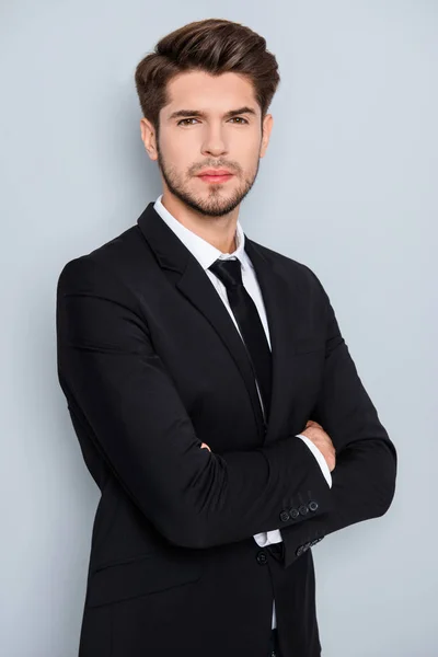 Portrait of serious young businessman in black suit with crosed — Stock Photo, Image