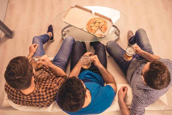 ビールとピザが付いているソファーに座っている 3 人の友人のトップ ビュー — ストック写真