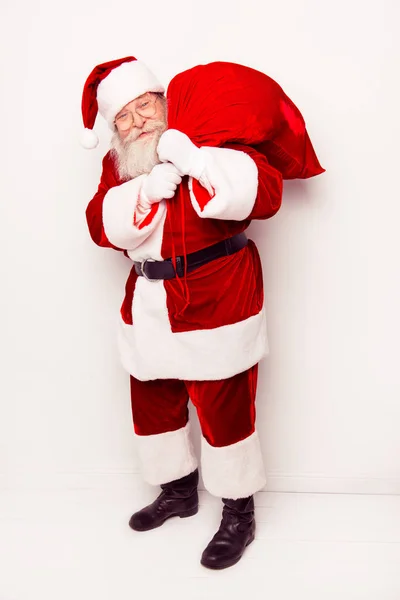 Смешной Санта-Клаус в красном костюме с большим тяжелым мешком в то время как — стоковое фото
