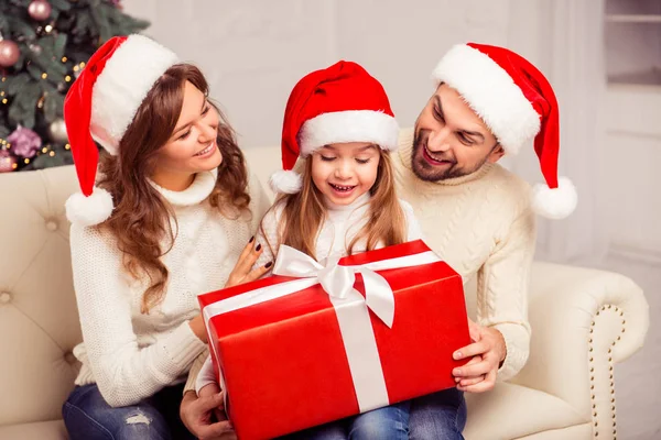 Feliz adorable padres dando regalo de Navidad a la pequeña hija — Foto de Stock