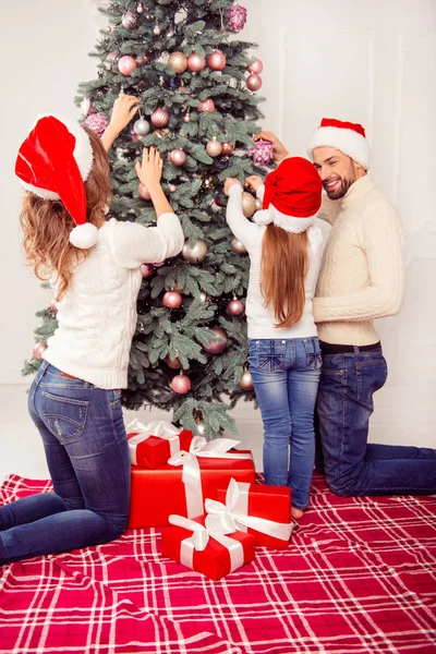 Família jovem em jeans se divertindo e decorando árvore de xmas na cov — Fotografia de Stock