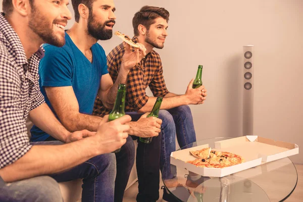 Vista lateral de tres hombres viendo televisión deportiva con cerveza y pizza — Foto de Stock