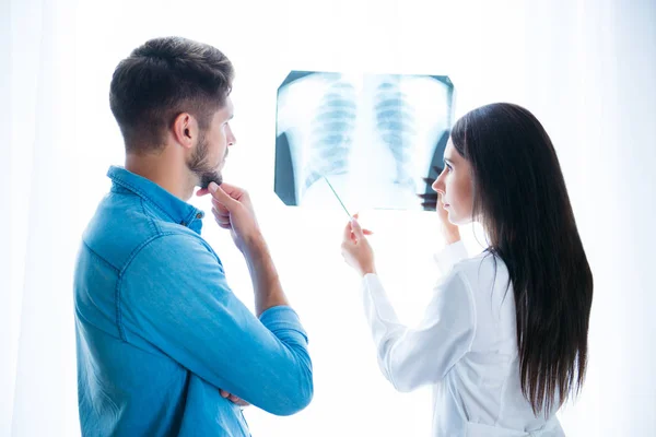 Doctora joven mostrando la foto de rayos X del pulmón a su paciente — Foto de Stock
