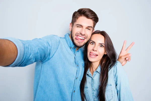 Engraçado casal mostrando línguas e gesto v-sinal ao fazer s — Fotografia de Stock