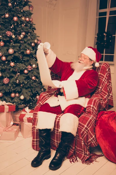 Papai Noel vestindo traje vermelho e sapatos pretos segurando lista de — Fotografia de Stock