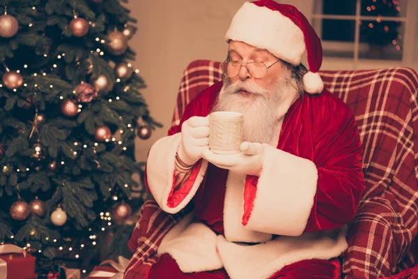 Tipo Papai Noel descansando vestindo traje vermelho perto de pinho segurando um — Fotografia de Stock