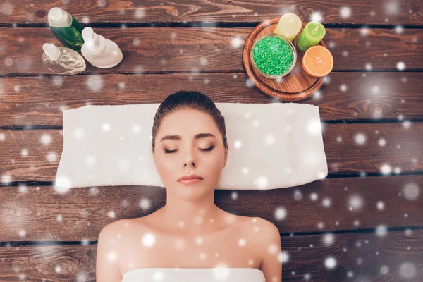 Mooie vrouw liggend in de sauna met lotions en kaarsen op sneeuw — Stockfoto
