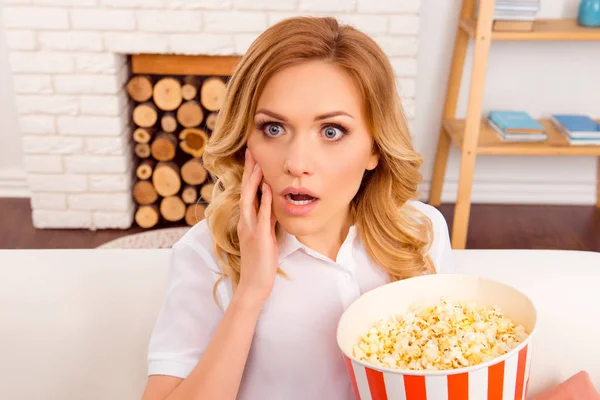 Шокированная молодая женщина смотрит фильм ужасов с попкорном — стоковое фото