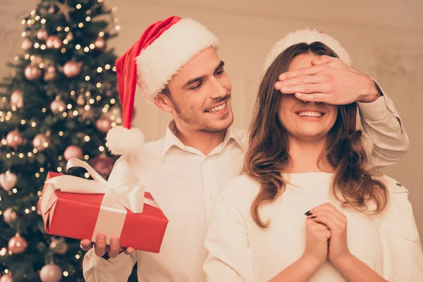 ชายที่มีความสุขในหมวกซานต้ากับของขวัญคริสต์มาสสีแดง ปิดตาของเขา — ภาพถ่ายสต็อก