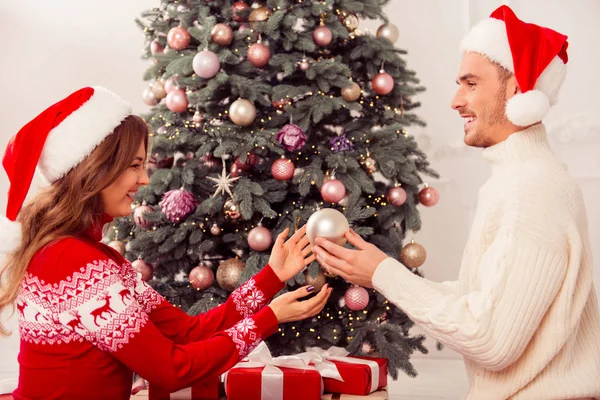 Gelukkige jonge paar dragen van santa hoeden voorbereiden op kerst — Stockfoto