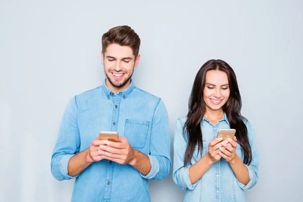 Feliz joven pareja en el amor escribiendo SMS en los teléfonos inteligentes — Foto de Stock