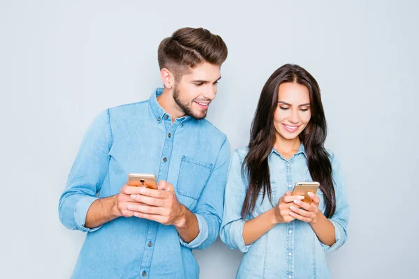 Молодой человек со смартфоном смотрит на свою девушку печатает смс — стоковое фото