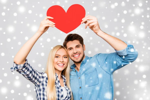 Joven familia sonriente sosteniendo el corazón de papel sobre fondo de Navidad — Foto de Stock