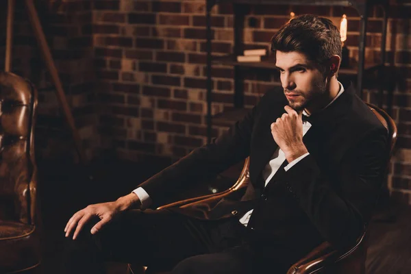 Schöner junger Bräutigam sitzt auf dem Sofa, während er wartet — Stockfoto