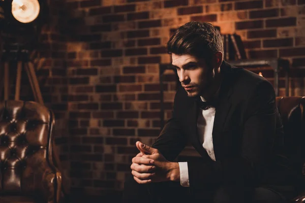 若い革のソファに座っている黒のスーツのビジネスマンの心 — ストック写真