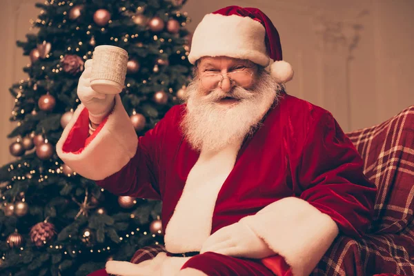 Wesoły Święty Mikołaj w czerwony strój, siedzi w pobliżu sosnowego i holdin — Zdjęcie stockowe