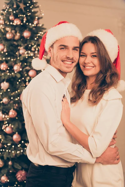 Portrait of happy cute couple near christmas tree having celebra