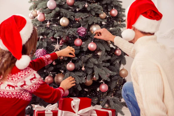 Paar verliefd Santa hoeden dragen en kerstboom versieren — Stockfoto