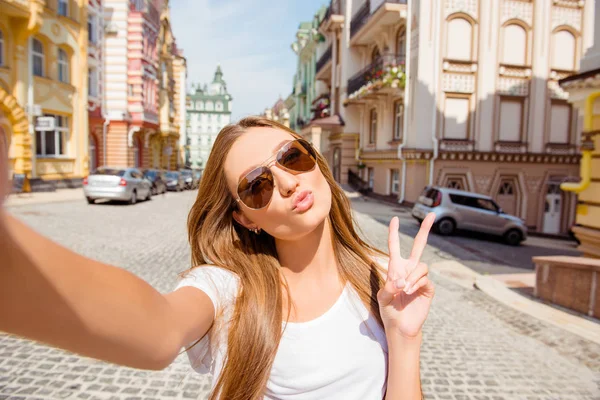 Menina muito feliz em óculos fazendo selfie, mostrando v-sign e p — Fotografia de Stock