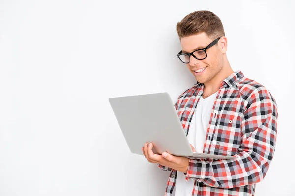 Lächelnder junger Mann mit Brille hält Laptop in der Hand und tippt — Stockfoto
