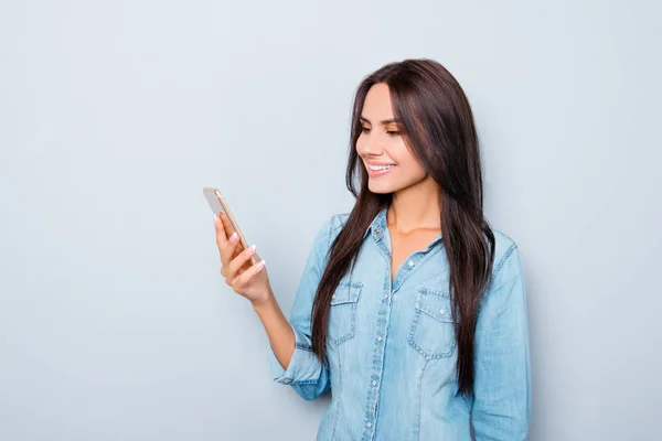 Uśmiechnięta dziewczyna czytanie wiadomości na telefon komórkowy na szarym tle — Zdjęcie stockowe
