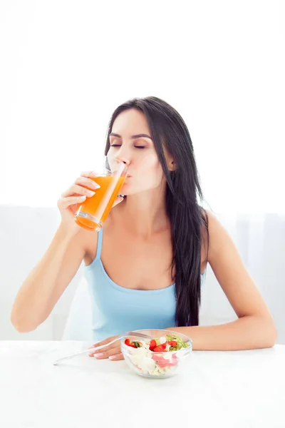 Mulher bonita com salada bebendo suco de laranja — Fotografia de Stock