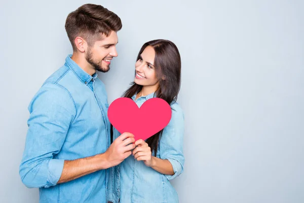 Dos amantes sosteniendo el corazón de papel sobre fondo gris —  Fotos de Stock