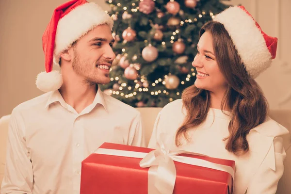 Retrato de casal bonito feliz em chapéus de santa com grande presente de xmas — Fotografia de Stock