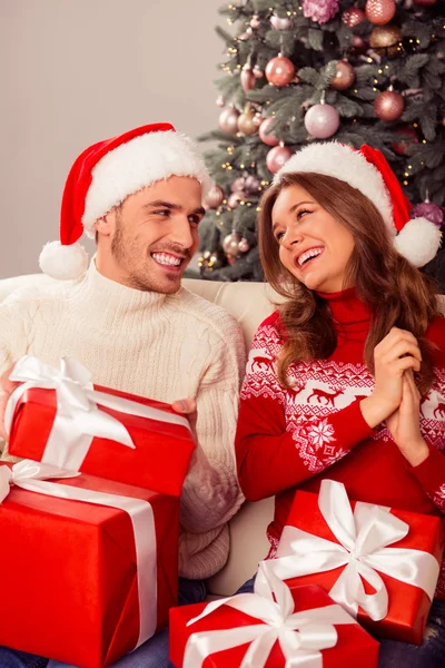 Красивий молодий чоловік в капелюсі Санта дарує різдвяний подарунок своїй дівчині — стокове фото
