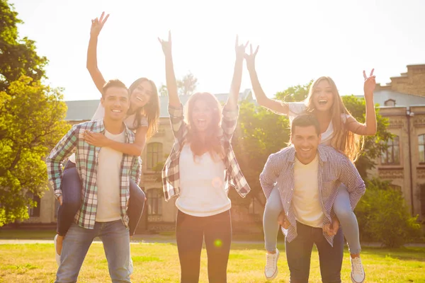 Attraktive fröhliche junge Freundinnen, die ihre Freundinnen tragen — Stockfoto