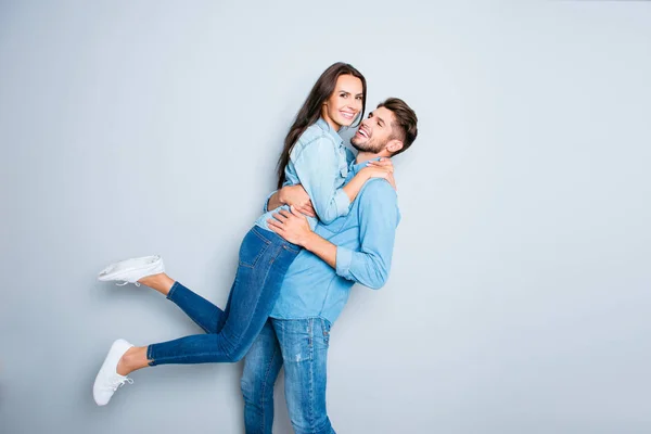 Lycklig man bär hans vackra hustru på grå bakgrund — Stockfoto