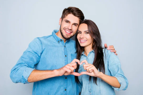 Retrato de dois felizes amantes sorridentes fazendo coração com os dedos — Fotografia de Stock