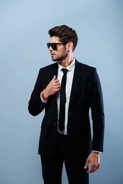 Young stylish businessman in black glasses touching suit — Stock Photo, Image