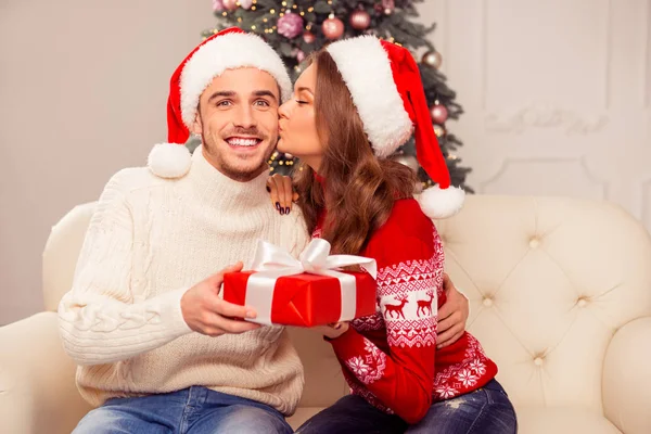 Mujer joven romántica dando regalo de Navidad al marido y besándose —  Fotos de Stock