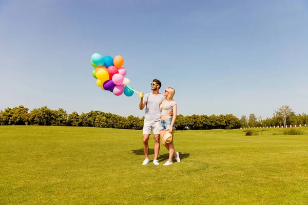 爱拥抱和拿着气球的幸福小两口 — 图库照片