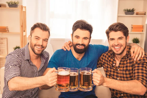 Porträtt av tre lyckliga män spottar med glas öl — Stockfoto